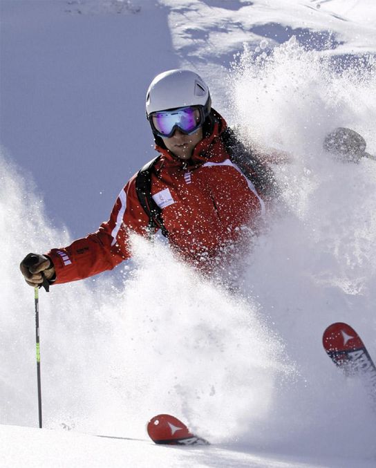 Skifahrer mit rotem Skianzug im Puderschnee